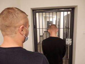 zatrzymany stojący przed kratami celi