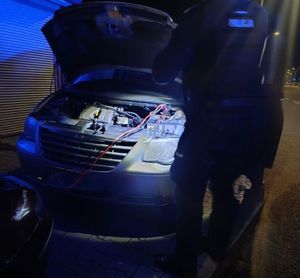 policjanci pomagający kobiecie uruchomić auto