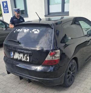 czarne auto i policjant